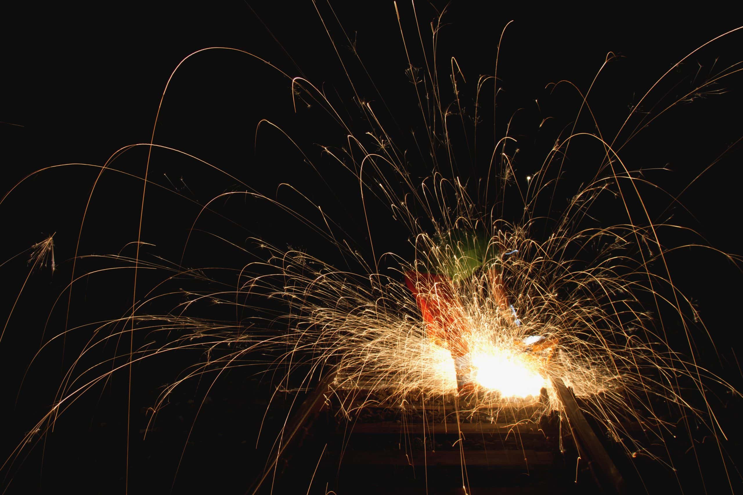 Sparks fly from a lit firework against the dark backdrop of Bonfire Night, creating bright, streaking lines of light.